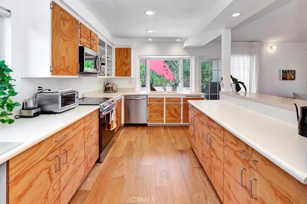 a large kitchen with stainless steel appliances granite countertop a lot of counter space and wooden floors