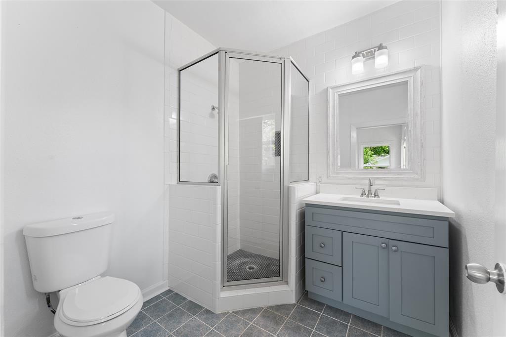 2405 Monroe Street Commerce, TX 75428 - Photo 23 of 31 a bathroom with a granite countertop toilet a sink and a mirror