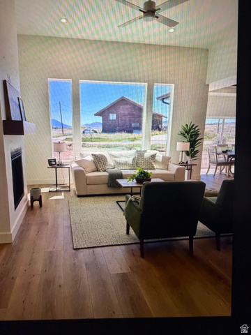 952 East Shilow Road, Unit 131 Erda, UT 84074 - Photo 2 of 12 Spacious living area featuring large picture windows, wood-finish flooring, a contemporary ceiling fan, and a built-in fireplace with a floating mantel