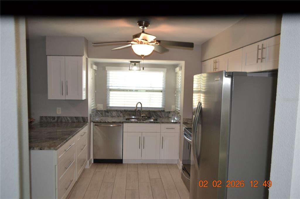 6204 West Knights Griffin Road Plant City, FL 33565 - Photo 3 of 19 a kitchen with stainless steel appliances granite countertop a sink a stove a refrigerator a washer dryer and white cabinets