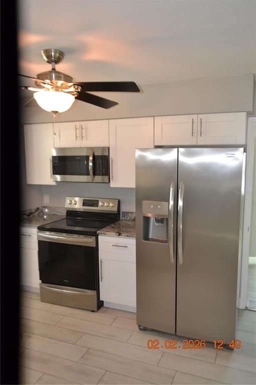 6204 West Knights Griffin Road Plant City, FL 33565 - Photo 4 of 19 a kitchen with stainless steel appliances granite countertop a refrigerator a stove and a microwave with wooden floor