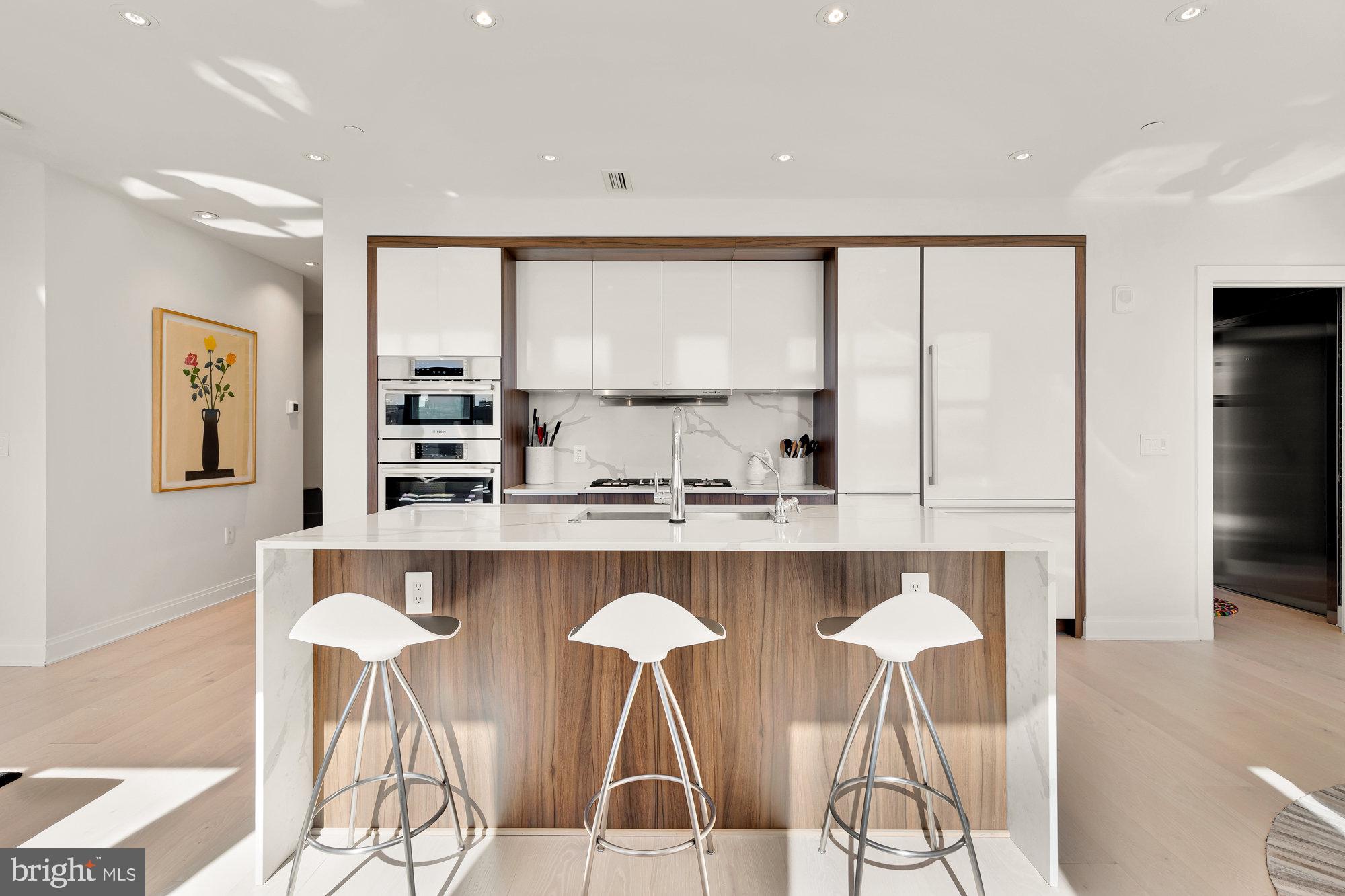 1427 Rhode Island Avenue Northwest, Unit PH01 Washington, DC 20005 - Photo 6 of 39 a kitchen with stainless steel appliances granite countertop a stove a sink and white cabinets with wooden floor