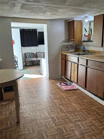 a living room with stainless steel appliances kitchen island granite countertop a stove top oven a sink a counter space and cabinets