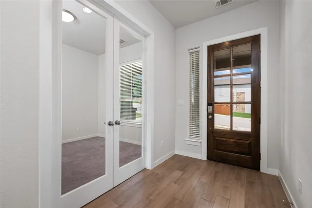 an empty room with wooden floor and windows