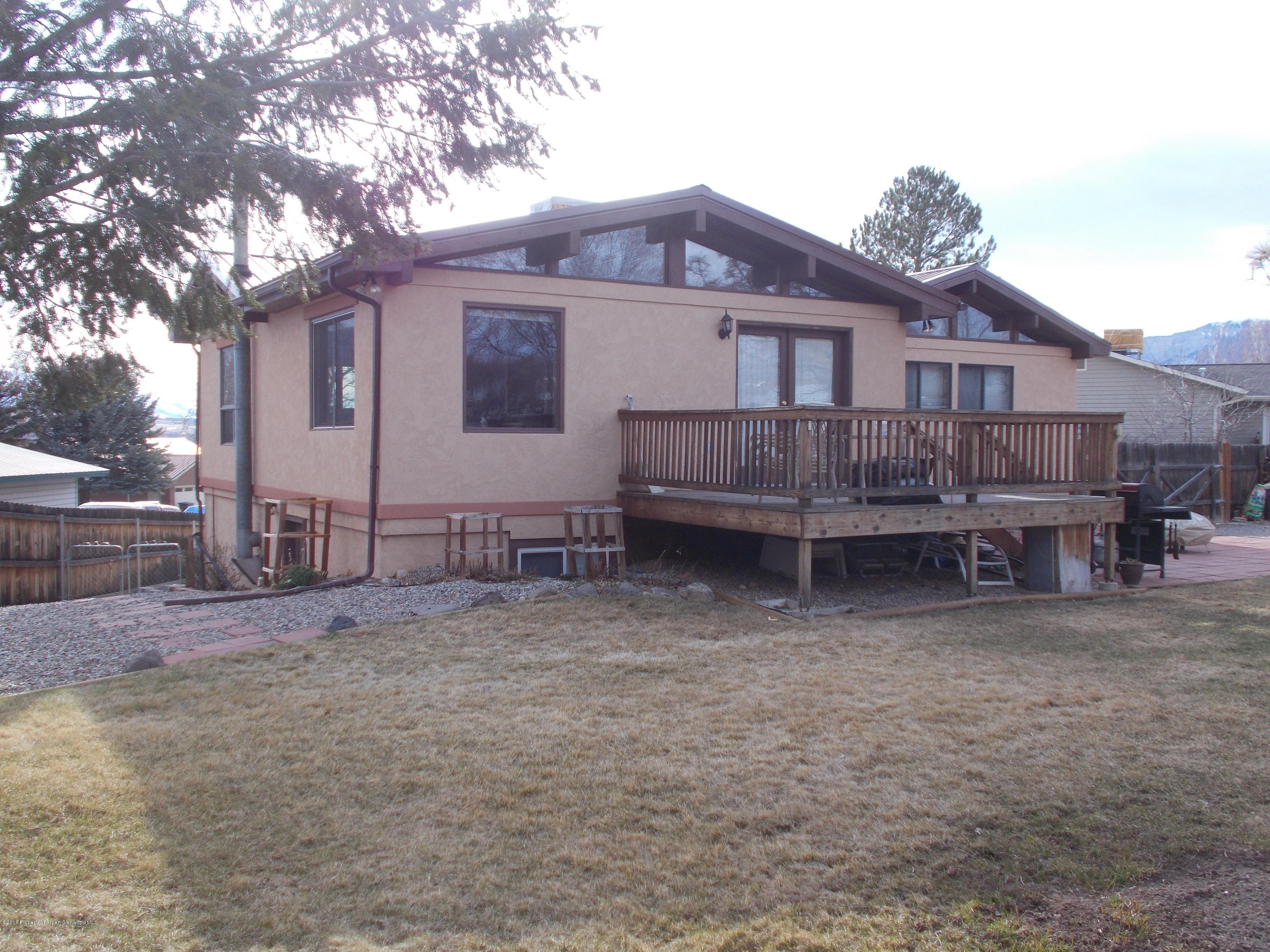 712 Buckeye Court Rifle, CO 81650 - Photo 4 of 22 a view of a house with a large tree and a yard