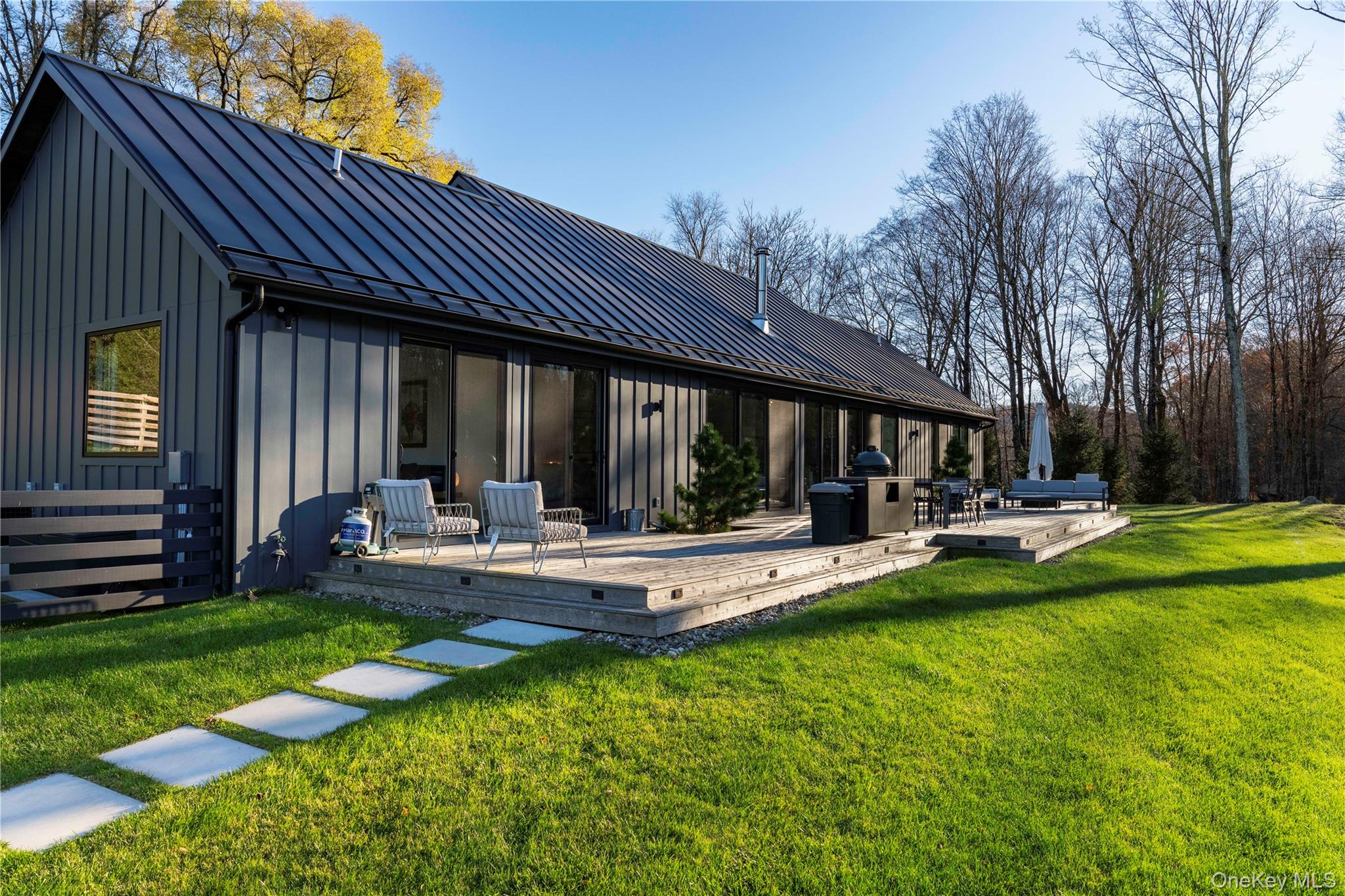 67 Dean Road Carmel, NY 10512 - Photo 2 of 29 Rear view of house featuring board and batten siding, a standing seam roof, a lawn, and a deck