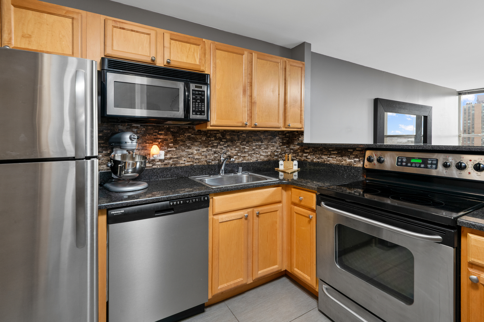 655 West Irving Park Road, Unit 705 Chicago, IL 60613 - Photo 4 of 9 a kitchen with granite countertop stainless steel appliances and wooden cabinets