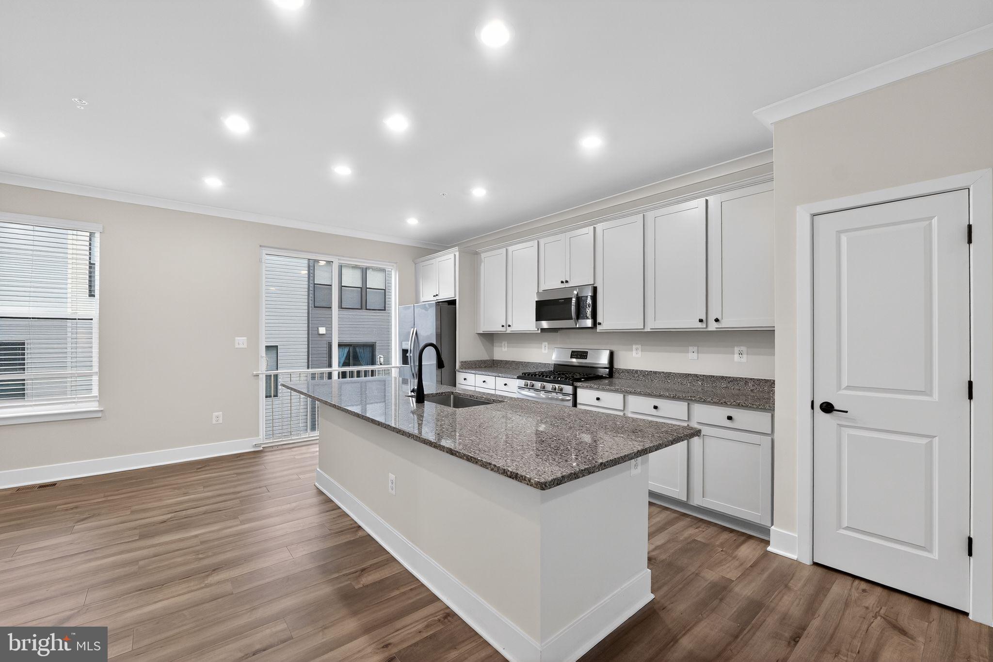 1505 Roland Heights Avenue Baltimore, MD 21211 - Photo 11 of 36 a large kitchen with granite countertop a stove top oven a sink a counter space and cabinets