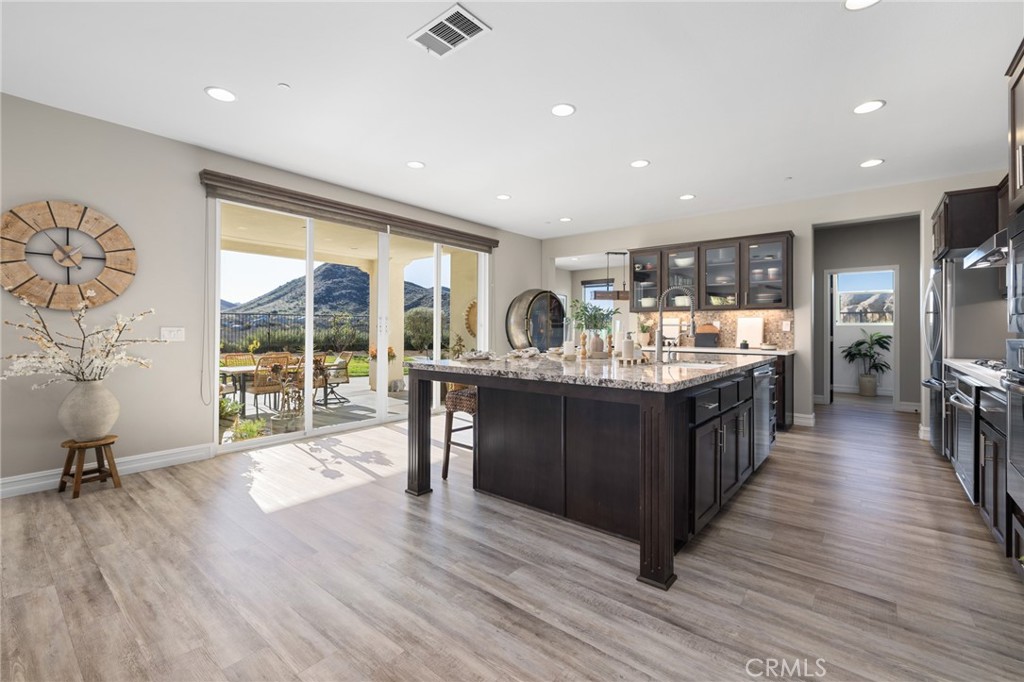 25313 High Noon Court Menifee, CA 92584 - Photo 21 of 73 a kitchen with stainless steel appliances granite countertop a refrigerator a sink dishwasher a stove and a dining table with wooden floor