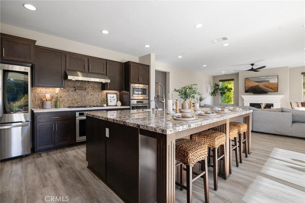 25313 High Noon Court Menifee, CA 92584 - Photo 29 of 73 a kitchen with stainless steel appliances kitchen island granite countertop a table chairs sink and cabinets