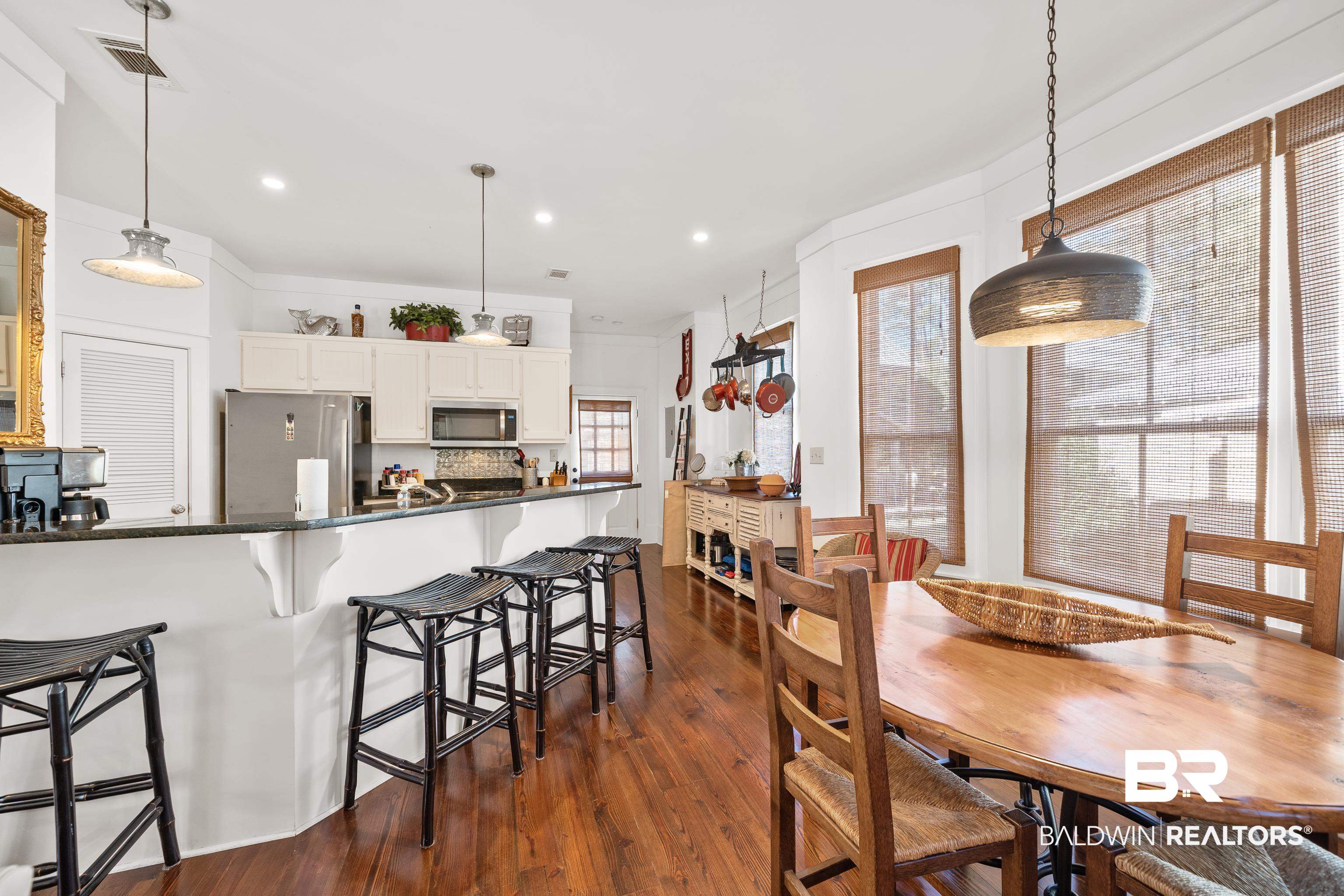 25773 Canal Road, Unit 10 Orange Beach, AL 36561 - Photo 7 of 40 Kitchen with beautiful hardwood floors, hanging light fixtures, decorative backsplash, white cabinetry, and stainless steel appliances