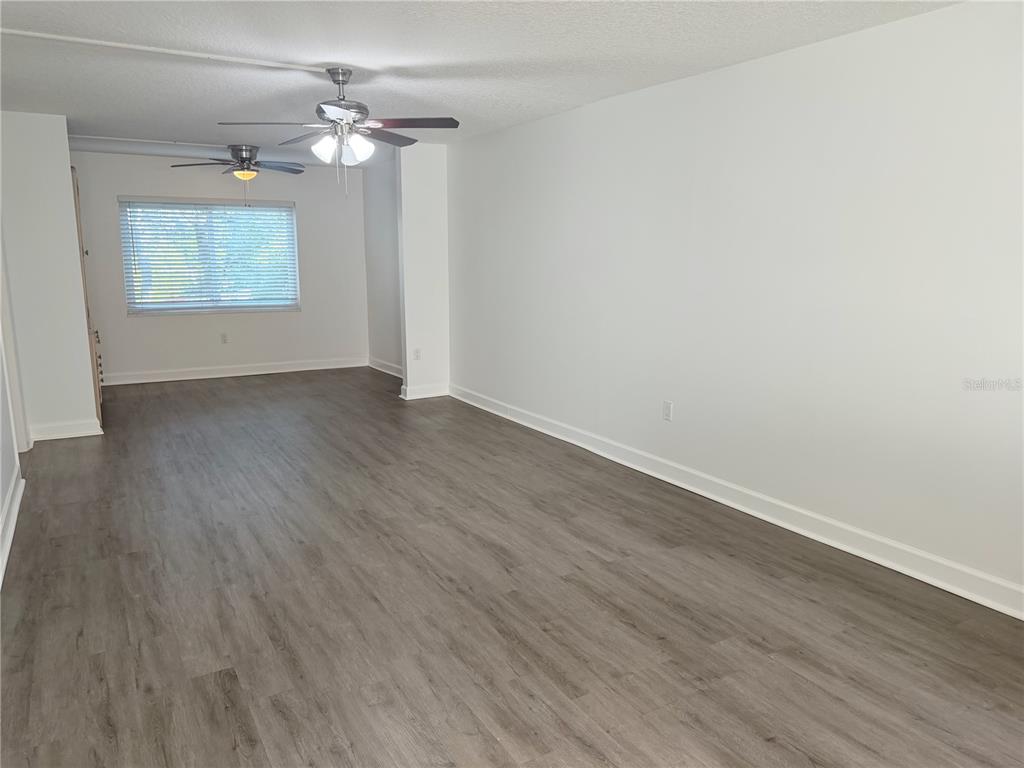 1524 Lakeview Road, Unit 305 Clearwater, FL 33756 - Photo 6 of 18 an empty room with wooden floor chandelier fan and windows
