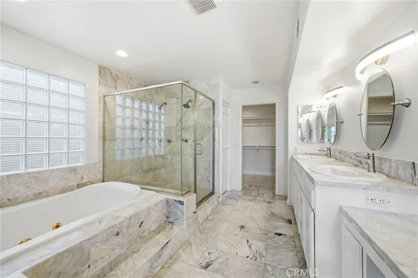a bathroom with a granite countertop sink a mirror a bathtub and shower