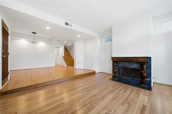 a view of an empty room with wooden floor fireplace and a window