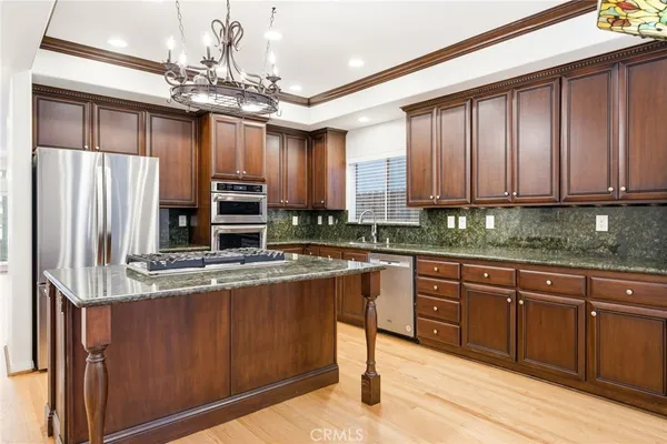 a kitchen with stainless steel appliances granite countertop a stove refrigerator a sink and dishwasher with wooden floor