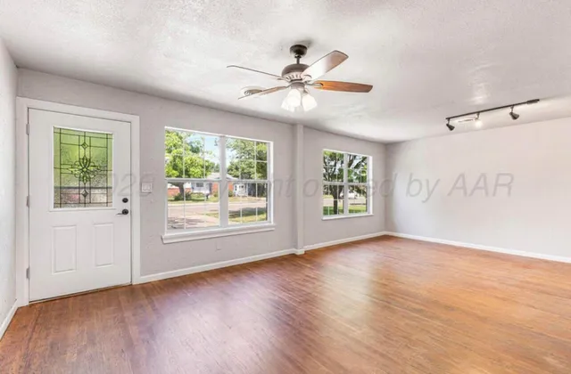 a view of an empty room with wooden floor and window