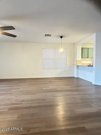 a view of empty room with wooden floor and fan