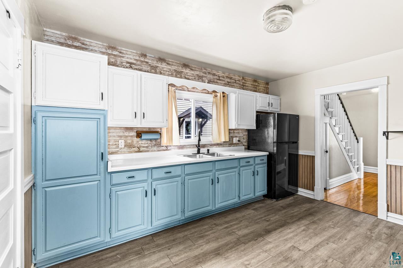 607 3rd Avenue East Superior, WI 54880 - Photo 13 of 41 Kitchen with dual tone cabinets, freestanding refrigerator, light countertops, tasteful backsplash, and dark wood-style floors