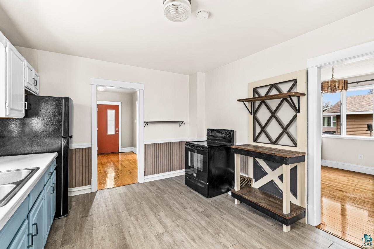 607 3rd Avenue East Superior, WI 54880 - Photo 15 of 41 Kitchen with black appliances, light countertops, light wood finished floors, wainscoting, and two tone cabinets