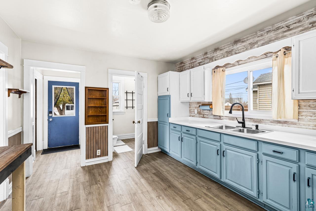 607 3rd Avenue East Superior, WI 54880 - Photo 16 of 41 Dual tone kitchen with dual tone cabinets, light countertops, plenty of natural light, dark wood-style floors, and decorative backsplash