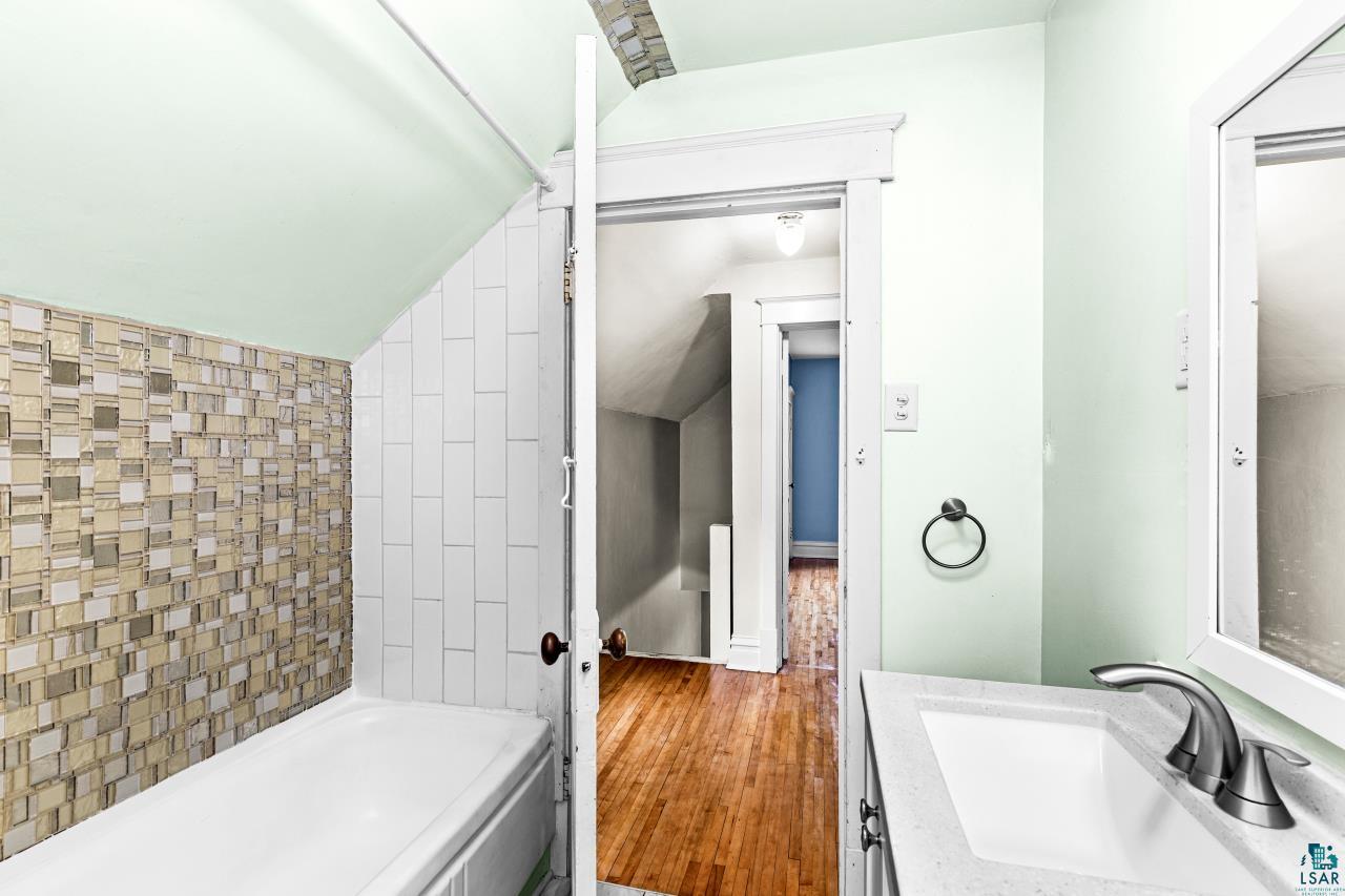 607 3rd Avenue East Superior, WI 54880 - Photo 22 of 41 Full bath with vanity, hardwood / wood-style flooring, lofted ceiling, and washtub / shower combination