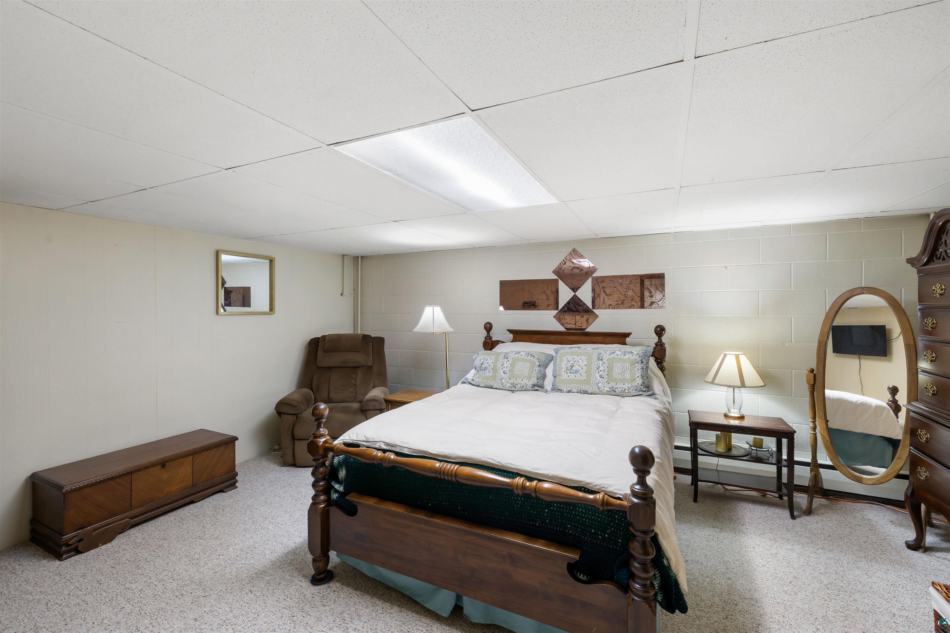 3975 Long Lake Shores Road Eveleth, MN 55734 - Photo 42 of 84 Bedroom featuring a paneled ceiling, a baseboard heating unit, and concrete block wall