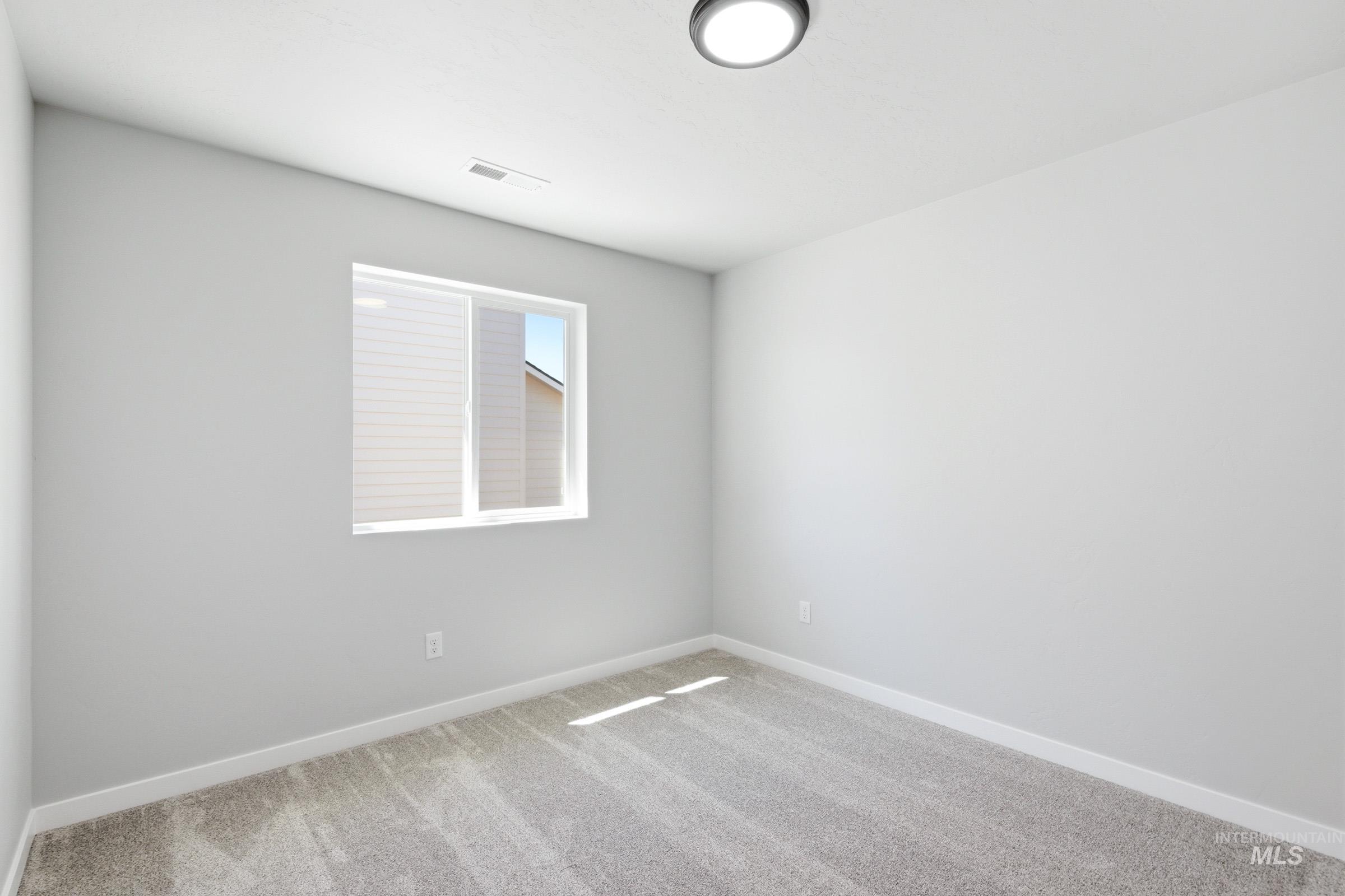 12805 Decatur Street Nampa, ID 83651 - Photo 13 of 20 Carpeted interior space featuring a single window with blinds, light gray walls, white trim, and a flush-mount ceiling light fixture