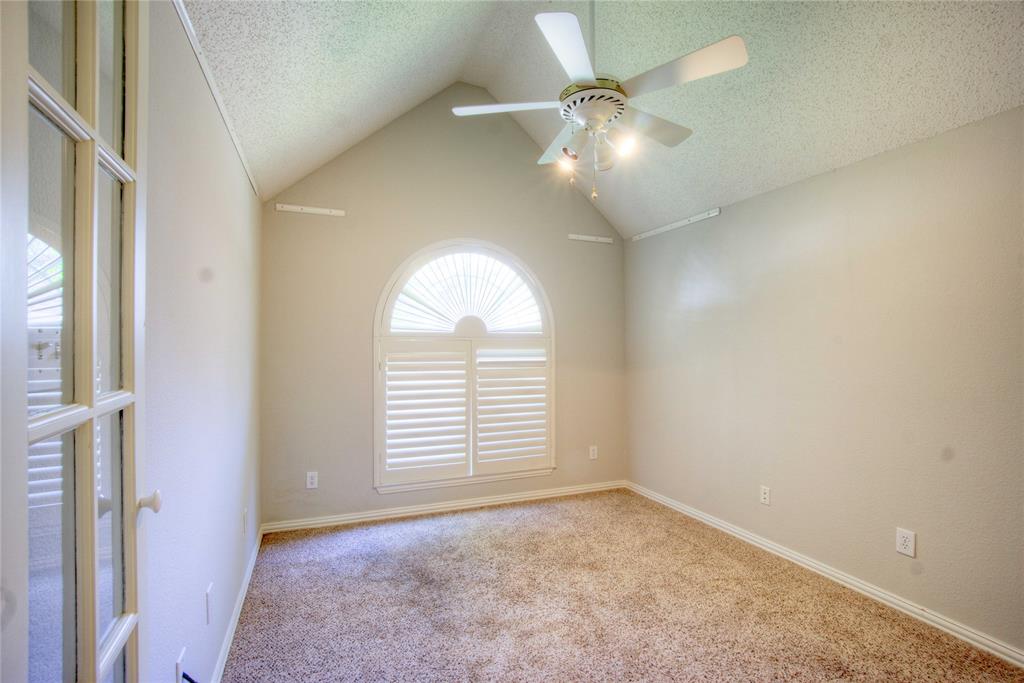 14584 Whitman Court Addison, TX 75001 - Photo 14 of 24 Carpeted spare room featuring vaulted ceiling, a textured ceiling, and a ceiling fan