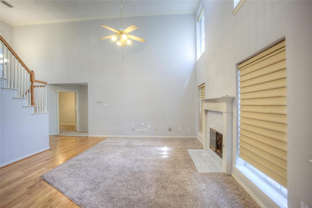14584 Whitman Court Addison, TX 75001 - Photo 7 of 24 Unfurnished living room with ornamental molding, a tile fireplace, a high ceiling, a ceiling fan, and a textured ceiling