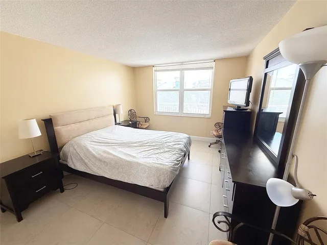 a bedroom with a bed and a large mirror next to a window