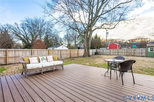 a backyard of a house with large trees and wooden fence
