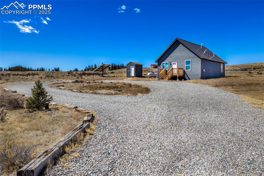 Back of house with a shed, gravel driveway, and an outdoor structure