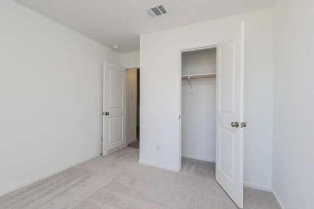 a view of an empty room with closet and a window