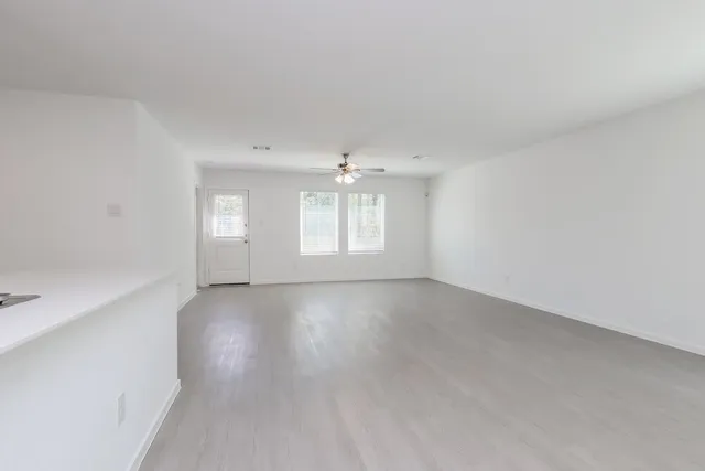 an empty room with windows and ceiling fan