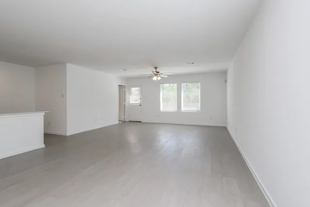 an empty room with windows and ceiling fan