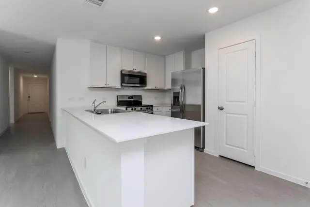 a kitchen with kitchen island white cabinets and stainless steel appliances