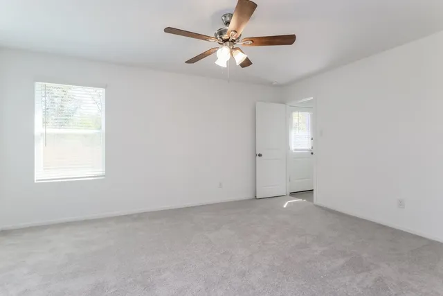 an empty room with windows and fan