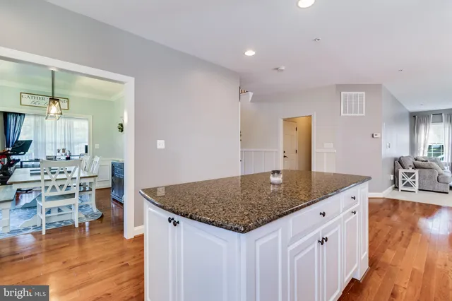 a kitchen with stainless steel appliances granite countertop a refrigerator a stove top oven a sink cabinets and wooden floor