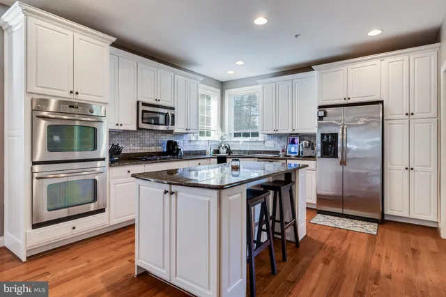 a kitchen with stainless steel appliances granite countertop a stove top oven a sink a dining table and chairs