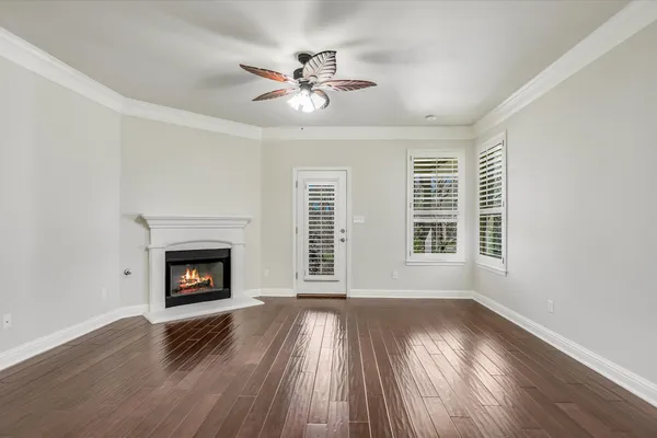 a view of an empty room with wooden floor fireplace and a window