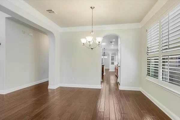 a view of a room with wooden floor chandelier and windows