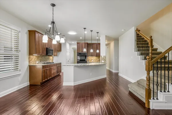 a view of a kitchen with a sink and dishwasher a stove top oven with wooden floor