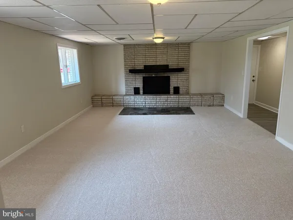 an empty room with fireplace a ceiling fan and windows