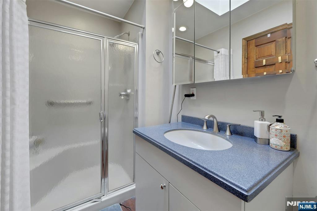 1280 Sussex Road Teaneck, NJ 07666 - Photo 17 of 36 a bathroom with a granite countertop sink a mirror and shower