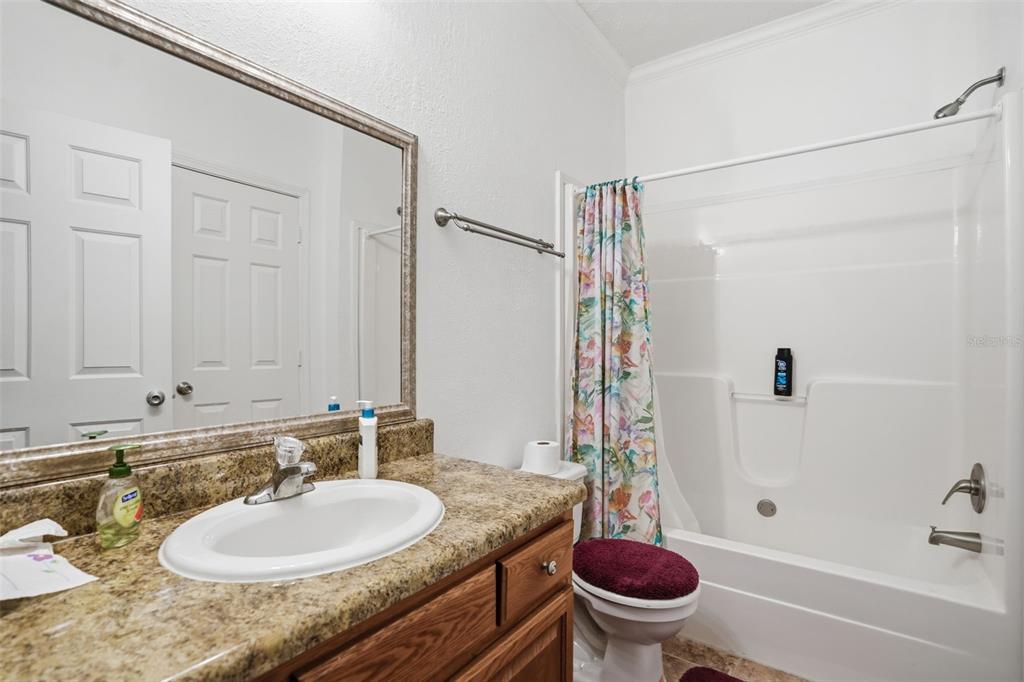 11805 Osprey Avenue Weeki Wachee, FL 34614 - Photo 18 of 34 a bathroom with a granite countertop sink a toilet a mirror and shower