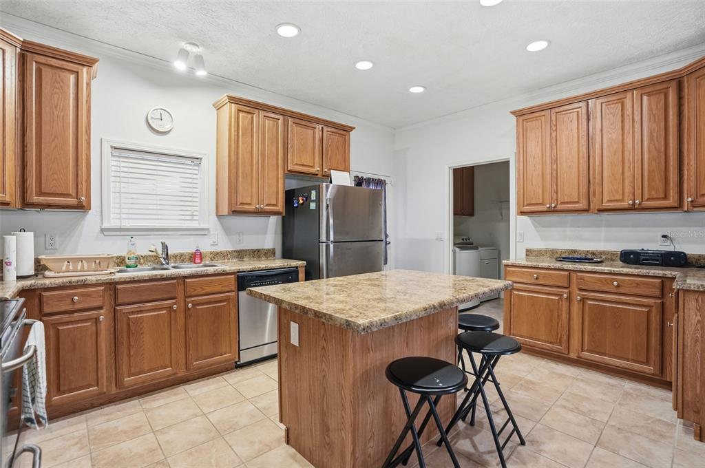 11805 Osprey Avenue Weeki Wachee, FL 34614 - Photo 6 of 34 a kitchen with stainless steel appliances granite countertop wooden cabinets a sink a stove a refrigerator and island