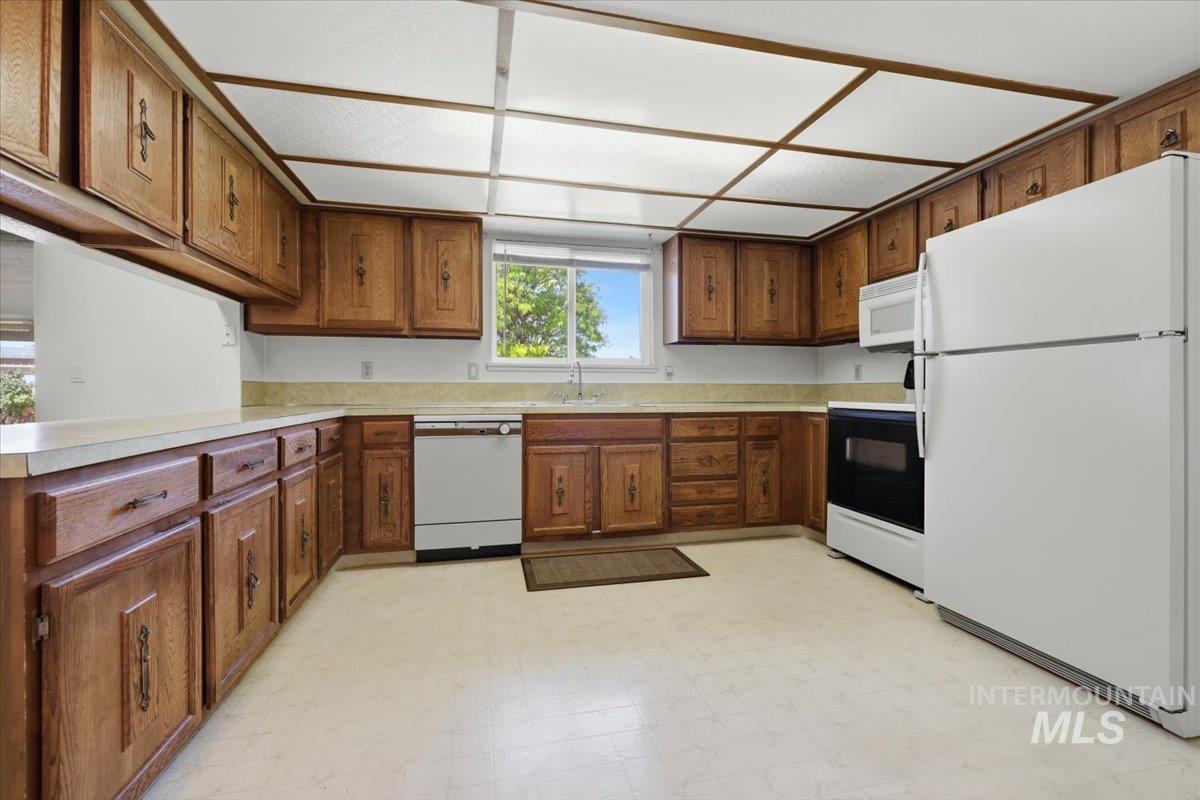 1311 North Middleton Road Nampa, ID 83651 - Photo 36 of 49 Kitchen featuring extensive wood cabinetry, light-toned countertops, window over sink, built-in dishwasher, and a luminous ceiling panel system