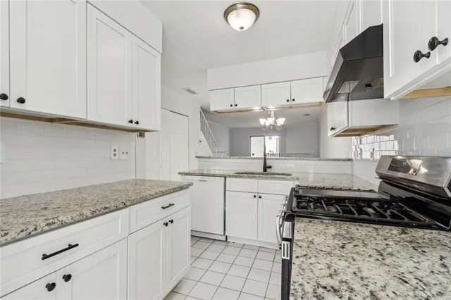 a kitchen with granite countertop white cabinets and white appliances