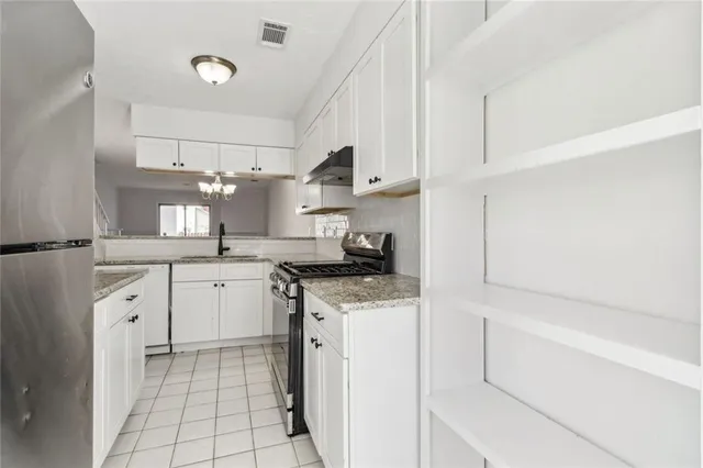 a kitchen with granite countertop a sink stove and cabinets