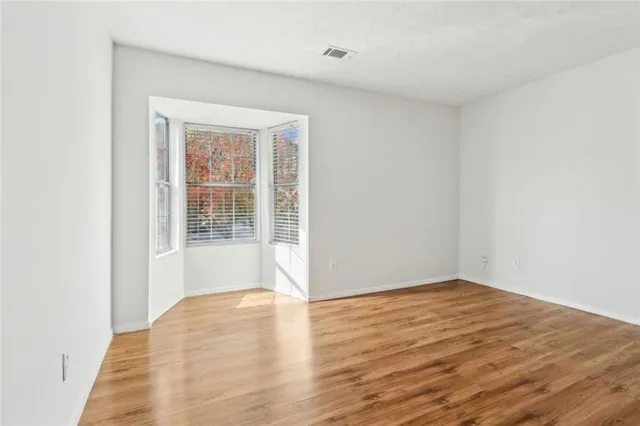 an empty room with wooden floor and windows